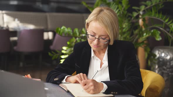 Portrait of Goodlooking Blond Business Lady Sitting at a Table During Business Meeting