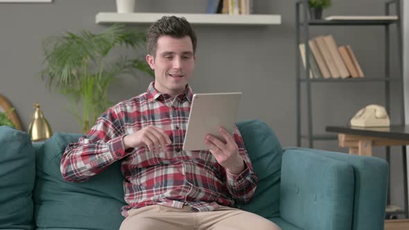 Man Talking on Video Call on Tablet on Sofa alt
