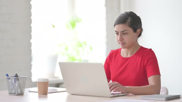 Indian Woman Looking at Camera While Using Laptop in Office alt