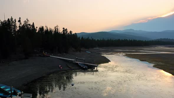 Flying over lake shoreline with low water and docks stretching to the water alt