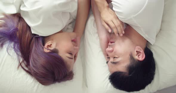 Loving young Asian couple spending a morning in bed at home.