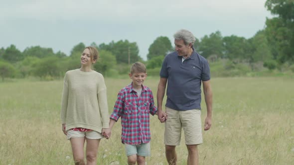 Family with one child walking through field together alt