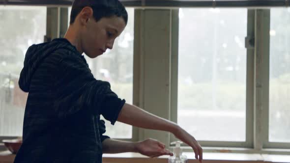 Corona pandemic - Boy using hand sanitizer to prevent coronavirus spread alt