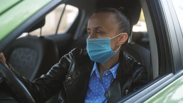 Woman in Medical Mask Sad Sitting Behind the Wheel of a Car During a Pandemic Coronavirus