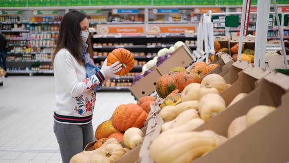 Female in Protective Mask Buying Pumpkin in Store alt