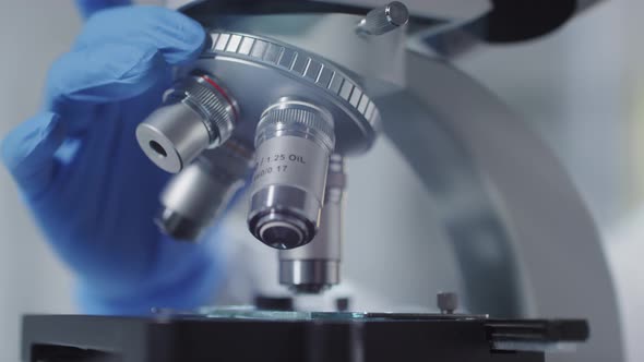 unrecognizable-scientist-revolving-nosepiece-of-microscope-stock-footage