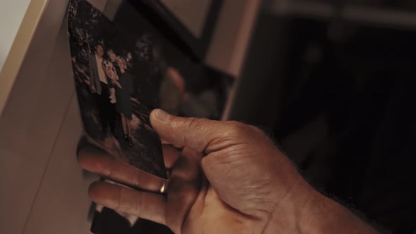 Man picks up a family photo from the iron door of his locker in the company locker room. Cinematic.