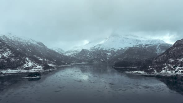 Flying above a frosen lake between Mountains in fogy day in Norway in december 2018 alt