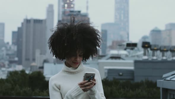 Afro American female on mobile phone on rooftop in Manhattan New York