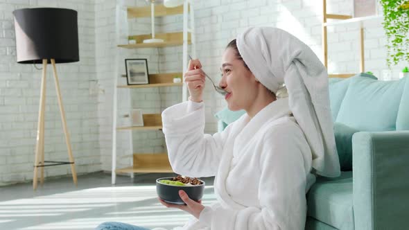 Lady Sitting Near Sofa After Shower and Laughing Eating Granola with Yogurt alt