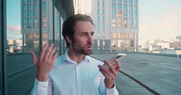 Smiling Young Man Recording Voice Recognition Message on Speakerphone alt