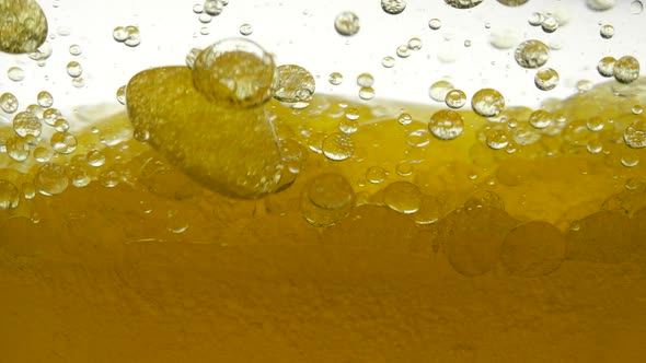 Close-up View of Golden Liquid in a Glass. Liquid Yellow Wave Line. Middle View of Large and Small alt