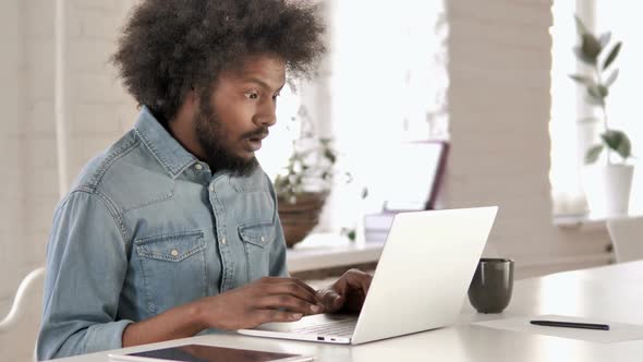Shocked Creative African Man Wondering and Working on Laptop alt