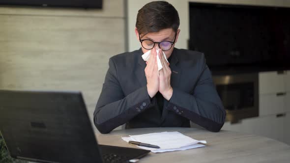 Sick Young Man at Work Got Allergy or Flu Sneezing Runny Nose Wiping Runny Nose with Paper Napkin alt