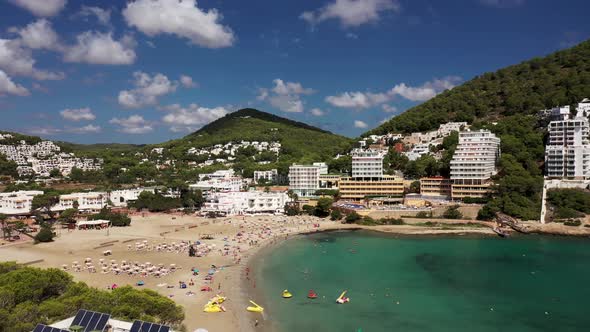 Aerial footage of the Spanish island of Ibiza showing the beautiful beach front and hotels alt