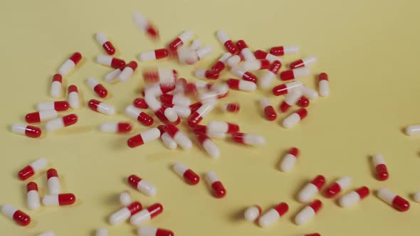 Slow motion high-angle medium shot as a handful of pills fall vertically. alt