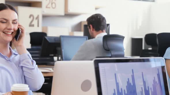 Female executive talking on phone while colleagues working in background 4k alt