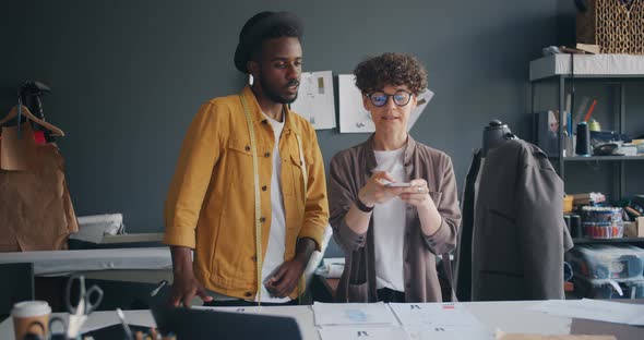 Colleagues Designers Using Smartphone Camera To Shoot Flat Lay of Sketches alt