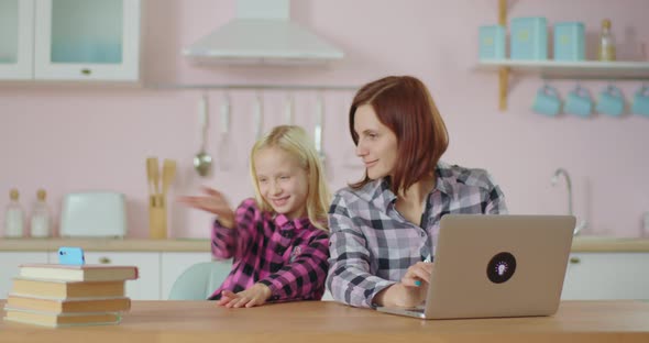 Young School Girl Recording Video Blog on Mobile Phone with Mother Working on Laptop Nearby. Smiling alt