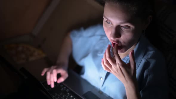 girl eats pizza and works at a laptop late at night alt