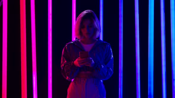 Portrait of a Young Stylish Woman Is Texting on Her Smartphone. Slow Motion. alt