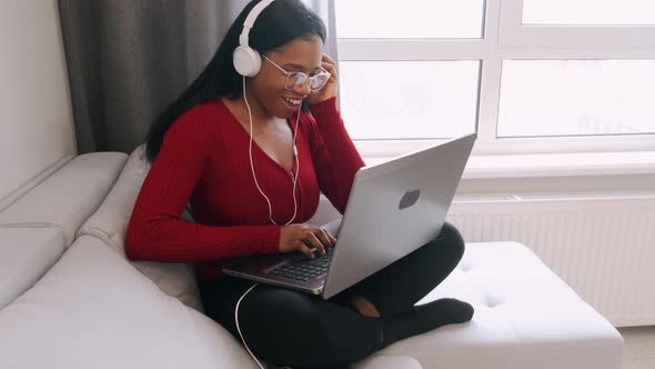 Young African Woman in Headphones with Laptop Working at Home alt