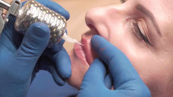 Process of Applying Permanent Makeup Tattoo of Red on Lips Woman