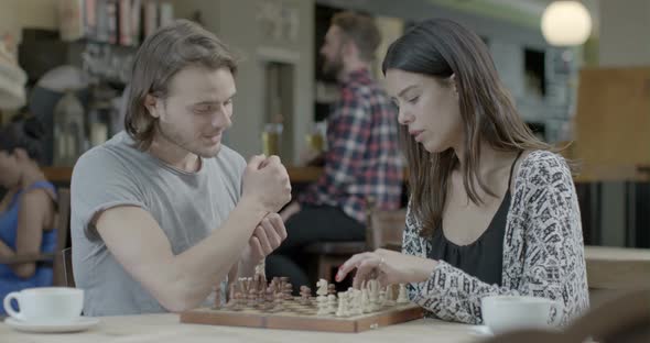 Man and woman playing chess while sitting in pub