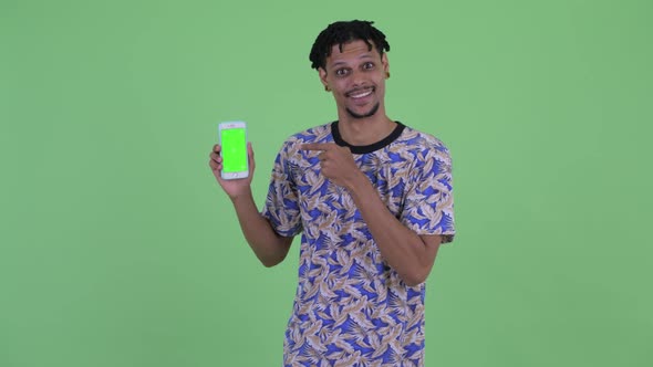 Happy Young Handsome African Man Showing Phone and Giving Thumbs Up alt