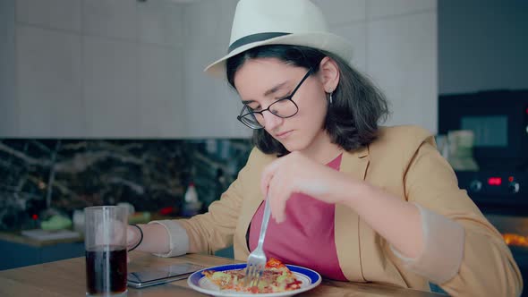 Cute Brunette Girl in Hat and Glasses Eating and Browsing Mobile App