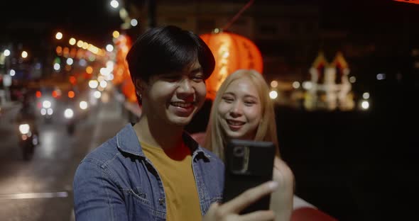 Young Asian couple travel make a video live streaming on social network by smartphone. alt