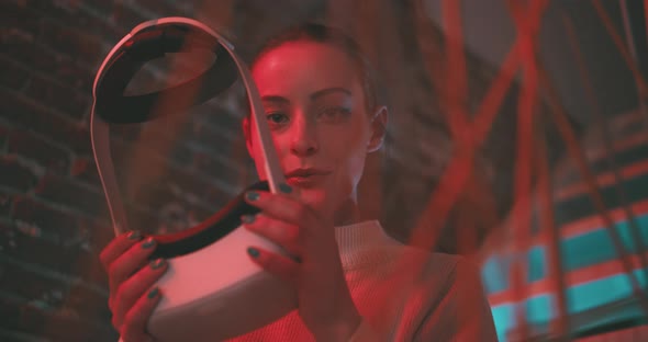 Young woman looking into the camera smiling then she puts on vr goggles alt