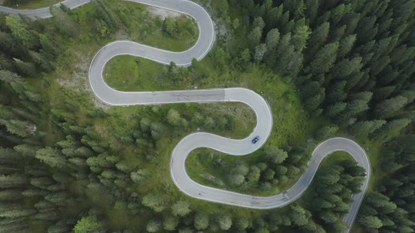 Town down aerial tracking view of sports car driving over winding German roads alt