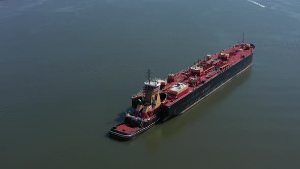 A drone view of a large red barge on the Hudson River in NY. Taken on a sunny day with small watercr alt