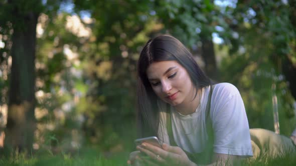 Attractive Woman Lies on Grass in Park and Use Mobile Phone Relax Summer