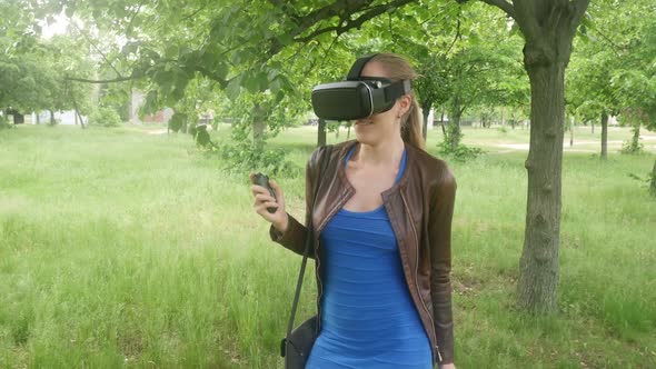 Sexy Young Girl In A Virtual Reality Helmet Uses A Virtual App In The Park