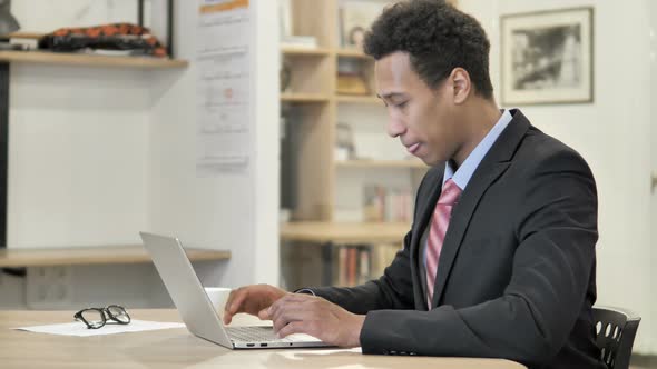 African Businessman with Back Pain Working on Laptop alt