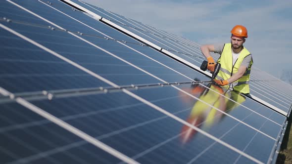 Male Engineer in a Uniform Is Checking the Solar Battery Outside alt