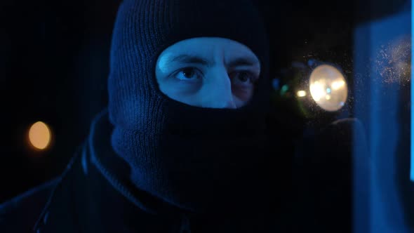 Closeup Concentrated Burglar with Flashlight Looking Through Window Running Away alt