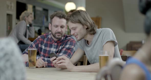 Men drinking beer and talking with each other while sitting in pub