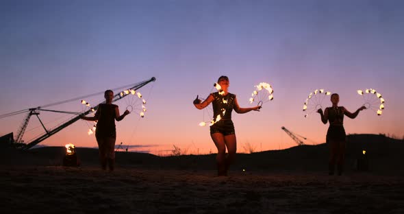 Fire Show Three Women in Their Hands Twist Burning Spears and Fans in the Sand with a Man with Two alt