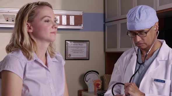 Doctor checking woman's heart with stethoscope