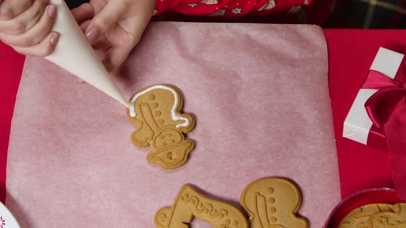 Woman in Red New Years Pajamas Is Icing a Traditional Gingerbread Cookie alt