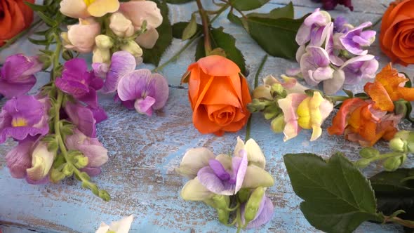 Colorful summer garden flowers: dragon flowers, roses, sweet pea on the vintage wooden alt