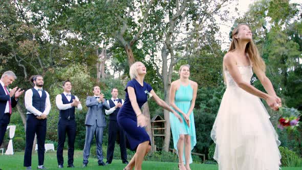 Bride throwing wedding bouquet to wedding guest  alt