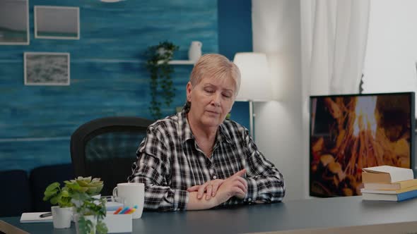 Senior Woman Talking and Listening Remote Colleagues During Video Call alt