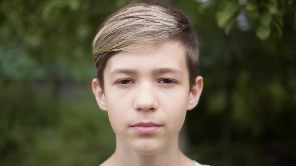 Portrait of a Boy with a Stylish Hairstyle Looks Down Shy
