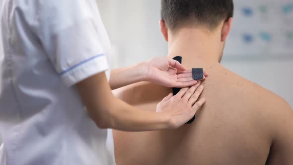 Doctor Applying Y-Shaped Tapes on Patient Upper Back Muscle Spasm Reducing alt