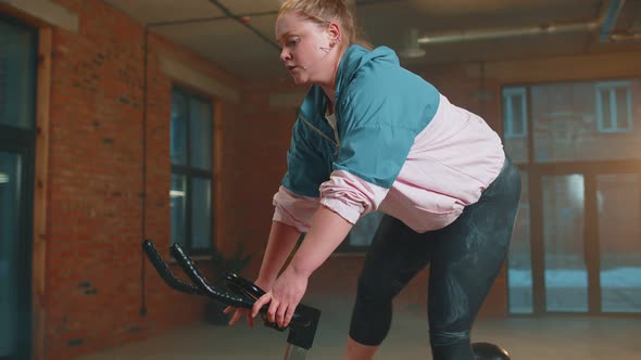Healthy Caucasian Woman Exercising Workout on Stationary Cycling Machine Bike in Gym Slow Motion alt
