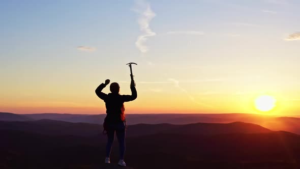 Dolly Zoom Effect of a Woman Happily Raises Her Hands Up on the Top of a Mountain at Sunset